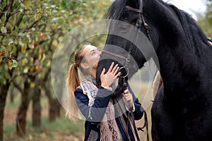 Beautiful stylish girl in a cowboy hat with a horse walking in the autumn forest, country style