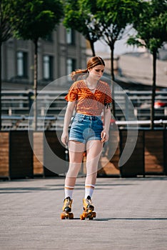 beautiful stylish girl in denim shorts roller skating