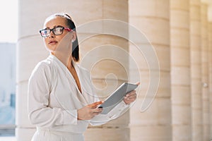 Beautiful stylish girl with glasses holding a digital tablet. Elegant business lady record data on remote work