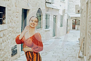 Beautiful stylish girl with long earrings, wearing an orange suit looks at the camera. Traveling around Europe Fashionable woman