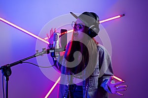 Beautiful stylish girl singing into a microphone in a recording studio