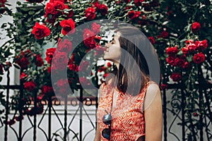 Beautiful stylish hipster woman smelling wonderful red roses in