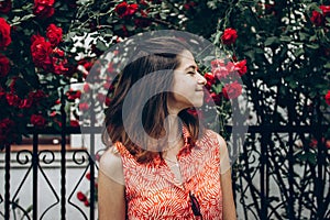 Beautiful stylish hipster woman smelling wonderful red roses in