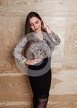 Beautiful stylish plus size girl with long hair posing over wooden background