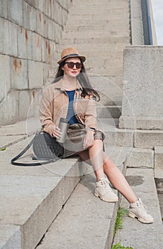 Beautiful stylish trendy young woman with cup of hot drink