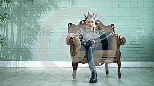 Beautiful stylish woman in a black leather crown sits in a chair in the studio