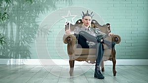 Beautiful stylish woman in a black leather crown sits in a chair in the studio