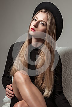 Beautiful stylish woman with blonde long hair in black dress and hat