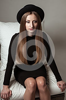 Beautiful stylish woman with blonde long hair in black dress and hat