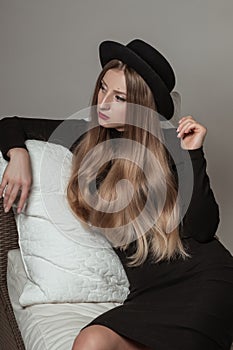 Beautiful stylish woman with blonde long hair in black dress and hat
