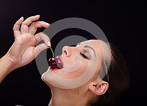 Beautiful, stylish woman eating a dark red cherry