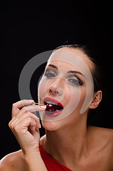 Beautiful, stylish woman eating a dark red cherry