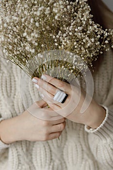 Beautiful stylish woman with modern square ring holding dried flowers, close up. Beauty and care