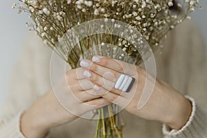 Beautiful stylish woman with modern square ring holding dried flowers, close up. Beauty and care