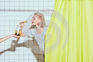 beautiful stylish woman taking pickled cucumber from glass jar