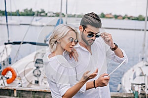 beautiful stylish young couple in sunglasses using digital tablet