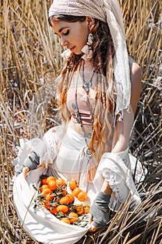 Beautiful stylish young girl holding tangerines in the hem of her skirt on the field