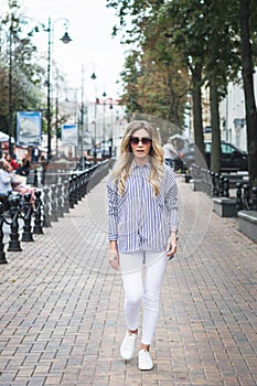 Beautiful stylish young girl posing for a photographer on the street