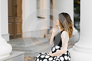 Beautiful stylish young pregnant woman holding her hand on her stomach