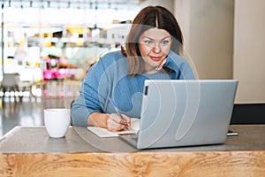 Beautiful stylish young woman plus size body positive using laptop at beauty salon office, small business owner