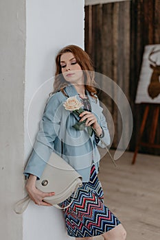beautiful stylishly dressed girl stands near the wall in the studio