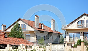 Beautiful suburban luxury modern house with red clay roof, balcony, fence, chimney, garage, patio