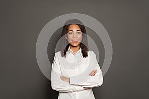 Beautiful successful happy smart African American woman with crossed arms on gray background