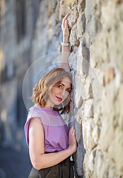 Beautiful successful middle aged woman posing against a stone wall street, photo shoot