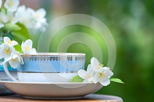 Beautiful summer composition of a cup of tea, book and Jasmine flowers on a natural green background, a concept of good morning,