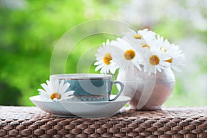 Beautiful summer composition of a cup of tea and daisy flowers o