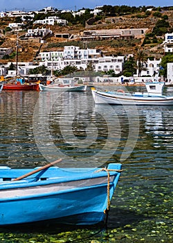 Beautiful summer day sunshine in Greek island port. Fishing boats. Small blue boat in foreground. Mykonos, Cyclades