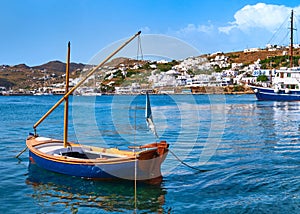 Beautiful summer day in typical Greek island. Fishing boats, whitewashed house. Small blue boat in foreground. Mykonos