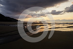 Beautiful summer golden sunset above the black sea with calm waves and reflection on the beach