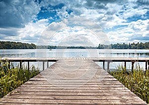 Beautiful summer landscape with dramatic sky, wooden pier on the