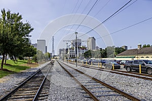 A beautiful summer landscape at the Dumaine Street RTA station with railroad tracks, parked cars, lush green trees and grass