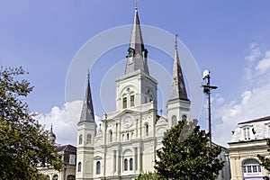 A beautiful summer landscape at Jackson Square with the St. Louis Cathedral, lush green trees, grass and plants, blue sky