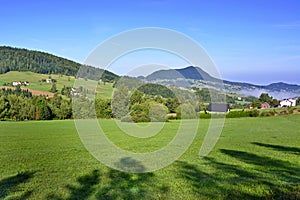 Beautiful summer landscape in the mountains with green meadows and forested hills