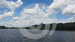 Beautiful summer landscape of the river. View from the river shore. Noon. The wind stirs the trees.