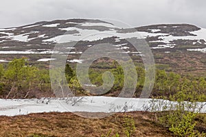 Beautiful summer landscape view of a snow covered mountain peak far up in northern Sweden, almost at the border into Norway. With