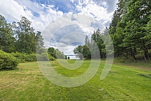 Beautiful summer nature landscape view. Greengrass field on front and Baltic sea on cloudy sky background