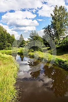 Beautiful summer river at sunny day with clouds reflection in the water