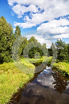 Beautiful summer river at sunny day with clouds reflection in the water