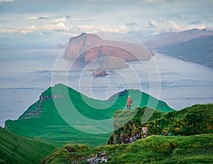 Beautiful summer scenery. Tourist admiring of sunset on Alaberg cliffs, Faroe Islands, Denmark, Europe