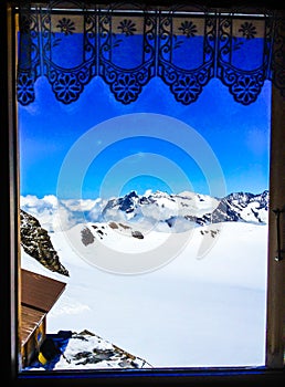 Beautiful summer scenic view on snowy Swiss Alps in sunny blue sky, window frame in foreground, Jungfrau Region, Bernese Oberland