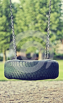 Beautiful summer season specific photograph. Old car tire used as a swing for children. Play time theme