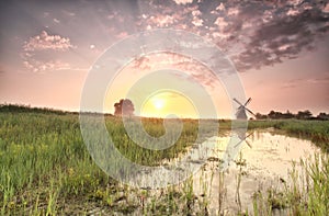 Beautiful summer sunrise over windmill by river
