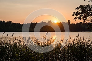 Beautiful summer sunset at the lake with blue sky, red and orange clouds