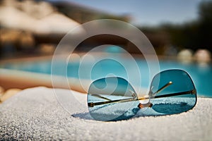 Beautiful sunglasses on the background of the pool. Relax by the pool. Sunglasses.