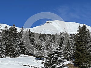 Beautiful sunlight and snow-capped alpine peaks above the Swiss tourist sports-recreational winter resorts