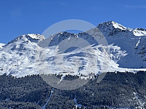 Beautiful sunlight and snow-capped alpine peaks above the Swiss tourist sports-recreational winter resorts